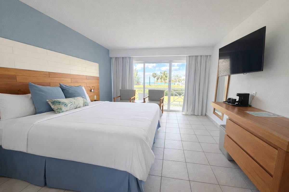 A hotel room with a bed, a TV, a desk, and a view of the outdoors.
