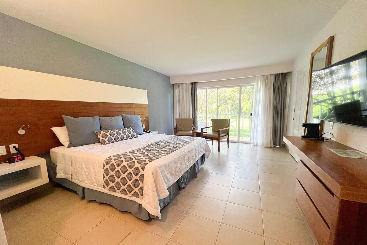Una habitación de hotel con una cama grande, televisión, escritorio y una silla.