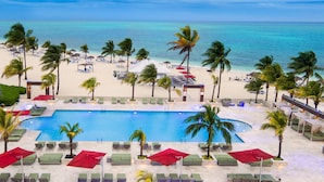 Un espace piscine d’un complexe hôtelier offrant une vue sur la plage et l’océan.