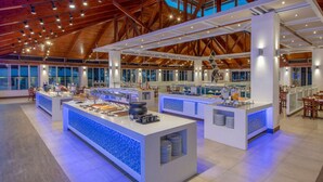 Un vaste espace buffet doté de plusieurs points de service, d’un plafond haut avec des poutres en bois et de grandes fenêtres laissant entrer la lumière naturelle.