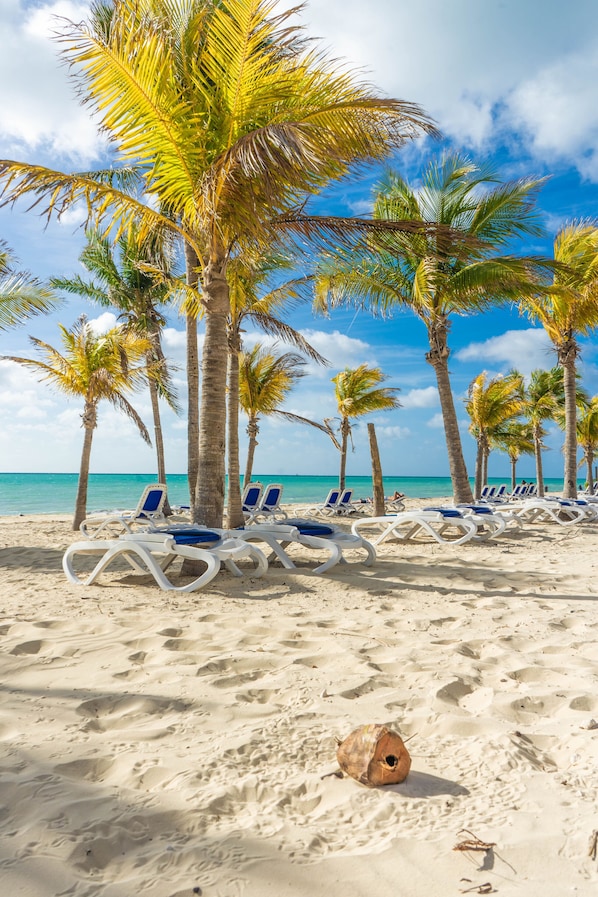 On the beach, white sand, sun-loungers, beach umbrellas