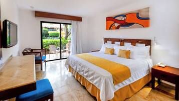 Ein Hotelzimmer mit Bett, Schreibtisch, Sessel, Fernseher und einem Bild an der Wand.
