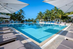 Una piscina al aire libre, sombrillas, sillones reclinables de piscina