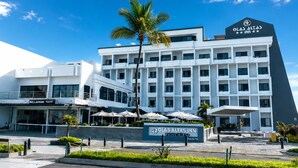 A modern hotel with a prominent sign for Olas Altas Inn, featuring a multi-story building with balconies and a clear sky.