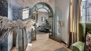 A modern living room with a large mirror, a green armchair, and a decorative plant. - Home Hotel Gabelshus (Oslo)