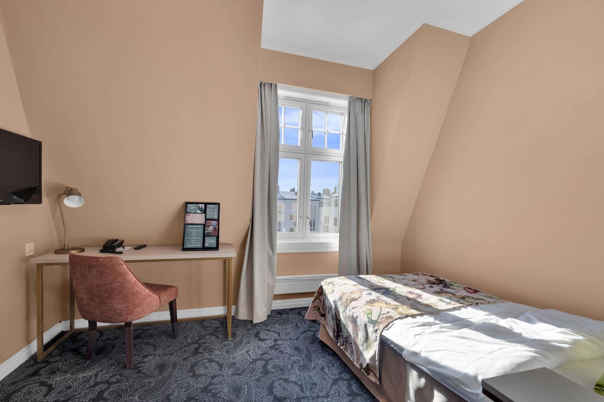 A bedroom with a desk, chair, and a bed.