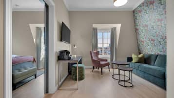 A modern living room with a sofa, a chair, a small table, a television, and a window with curtains.