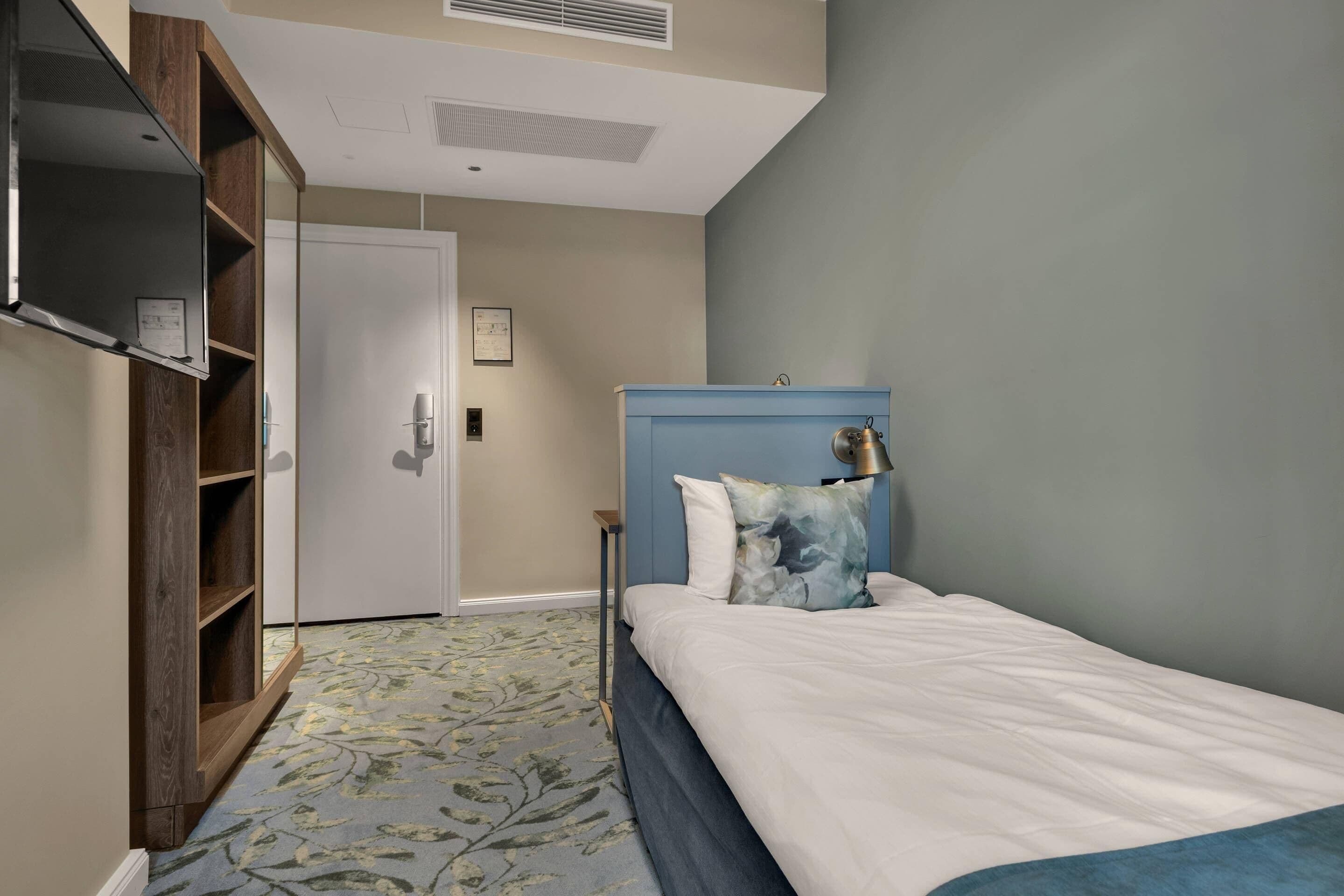 A bedroom with a bed, a wardrobe, a door, and a carpet.