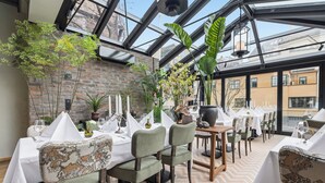 A restaurant with tables set for dining, chairs, and a brick wall. - Home Hotel Gabelshus (Oslo)