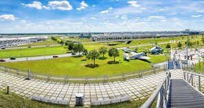 Un espacio amplio y abierto con un campo cubierto de césped, algunos árboles y algunos aviones estacionados.