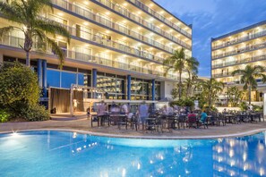 A hotel with multiple balconies, a pool area, and outdoor seating.