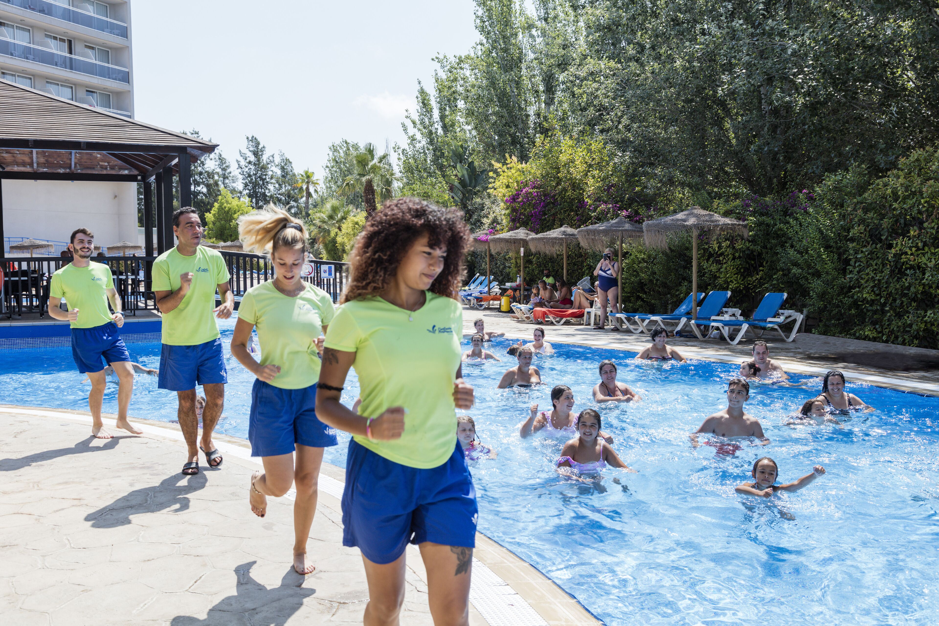 Zona de piscina con gente nadando y otros caminando.