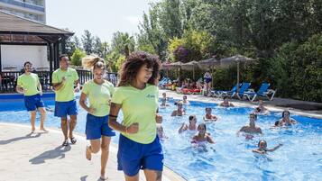 Zona de piscina con gente nadando y otros caminando.
