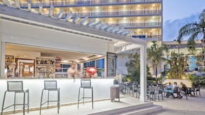 A hotel bar with outdoor seating and a view of the building's balconies. - Sol Costa Daurada (Salou)