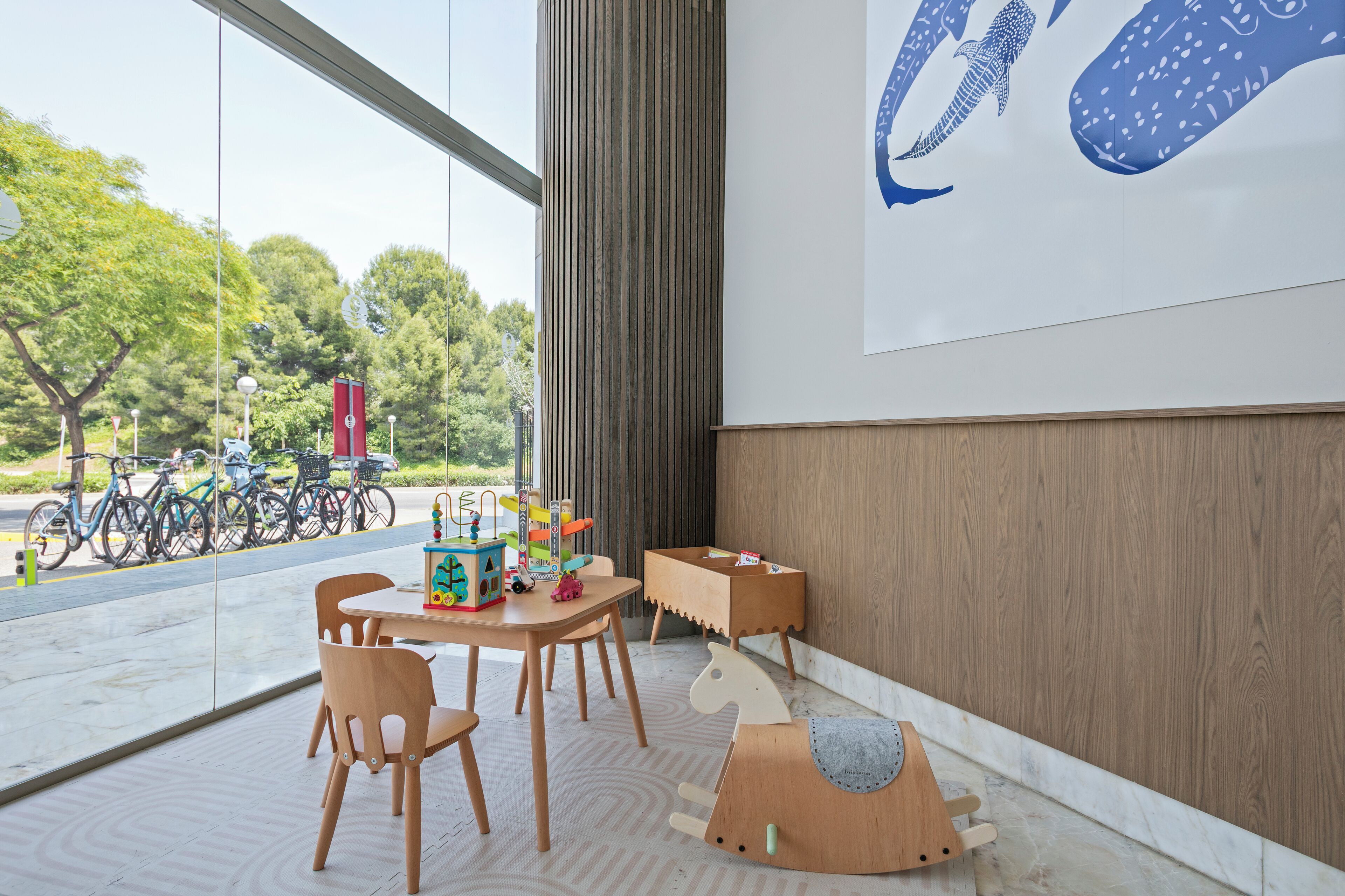 Un interior moderno con un ventanal grande, muebles de madera y una obra de arte colgada en la pared.