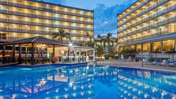 A hotel with a large outdoor swimming pool, multiple balconies, and a covered area with seating. - Sol Costa Daurada (Salou)