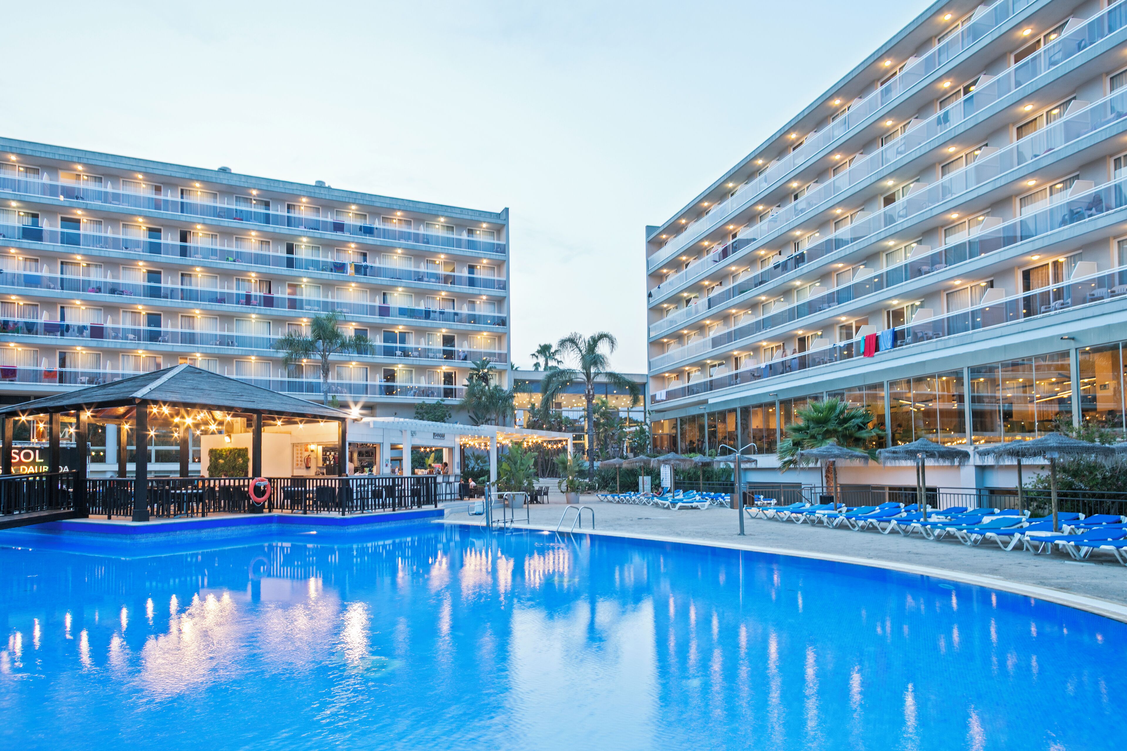 Un hotel con piscina, varios balcones y una zona de bar.