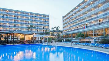 Un hotel con piscina, varios balcones y una zona de bar.