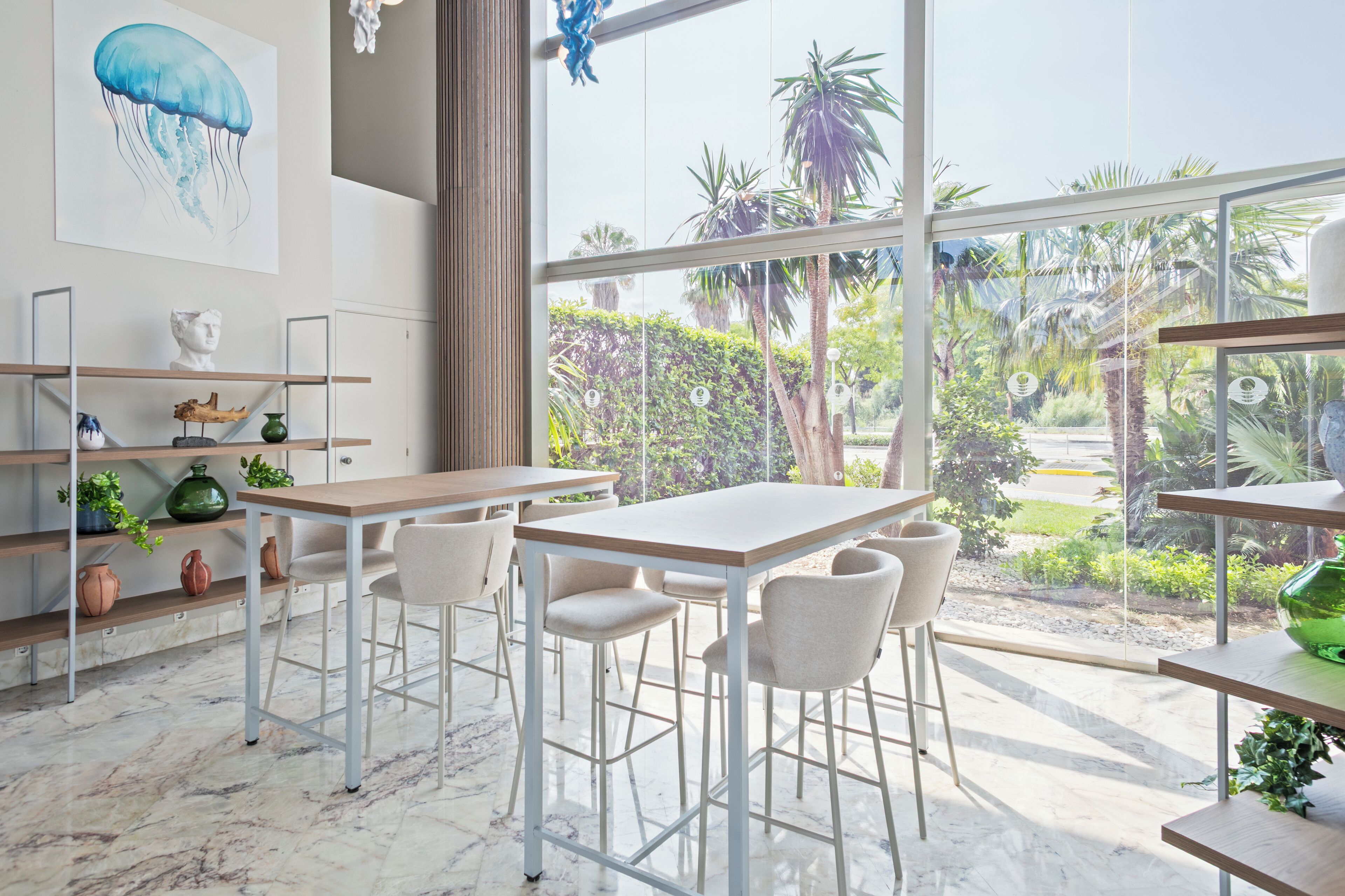 Una cocina moderna con un amplio ventanal, suelo de mármol y vistas a un jardín.
