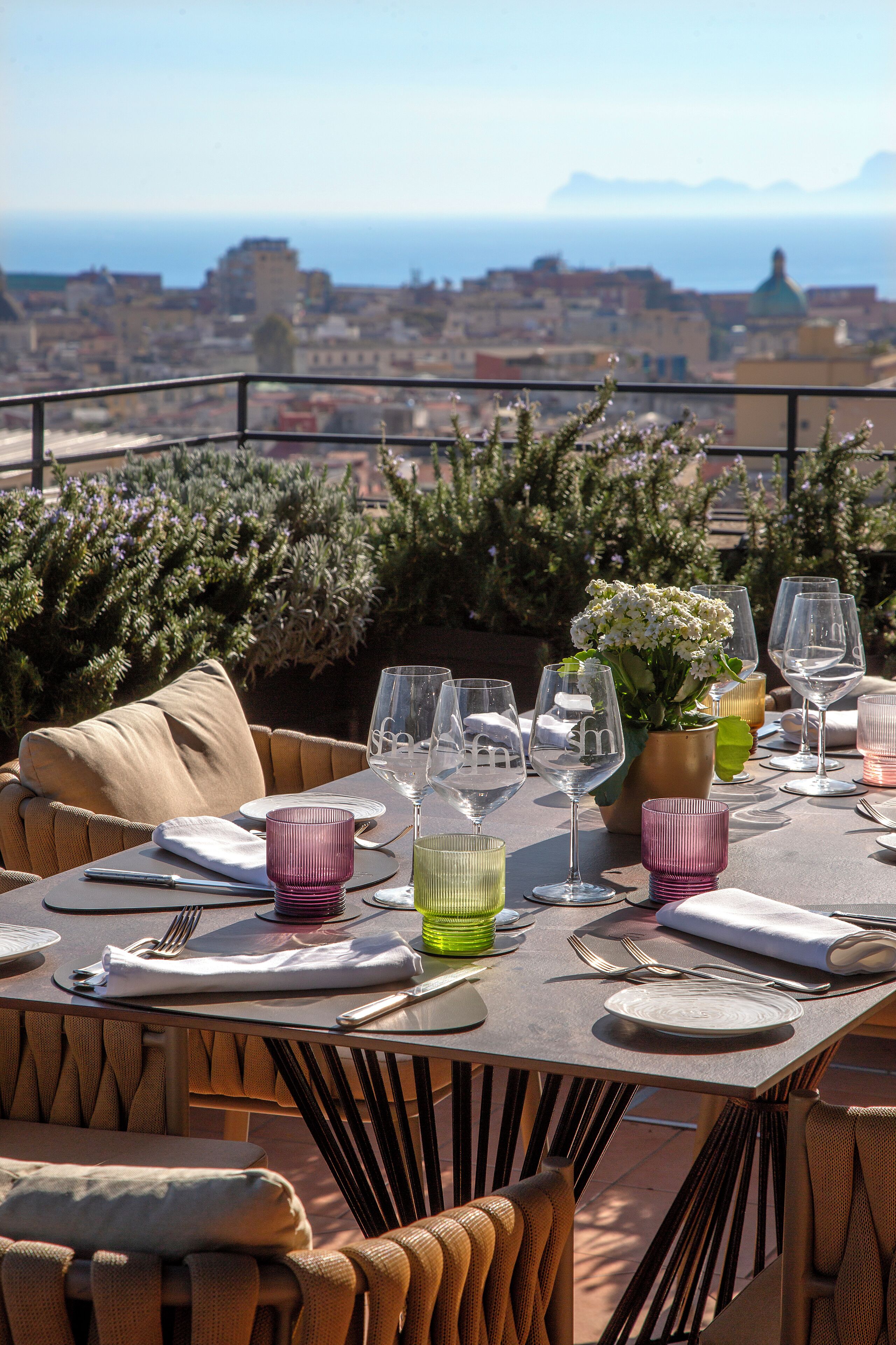 Tavola imbandita per la cena con vista sulla città e sull'oceano.