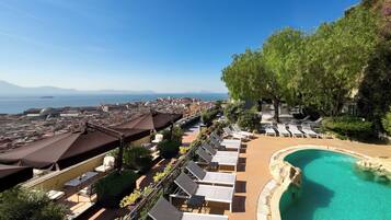 Un resort con piscina, tumbonas y vistas a la ciudad y al mar.