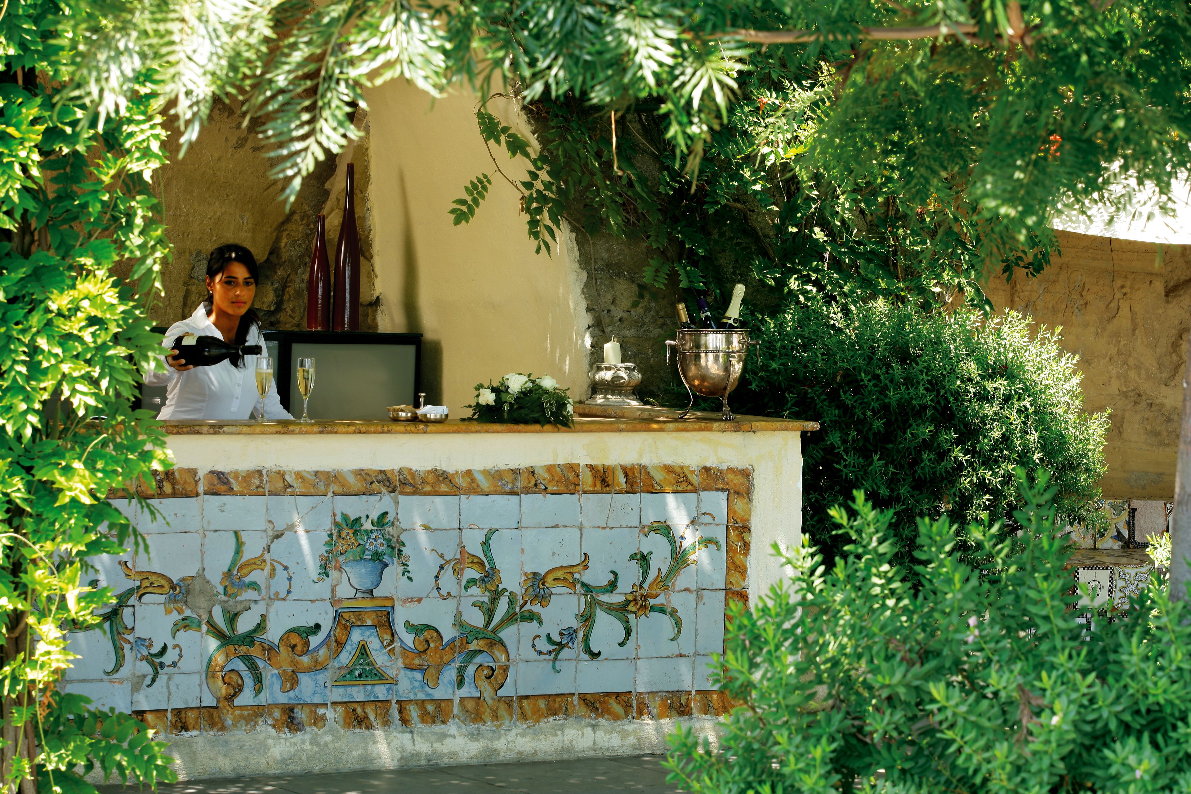 A bar area with a tiled backsplash, a wine bottle, and a candle on the counter.