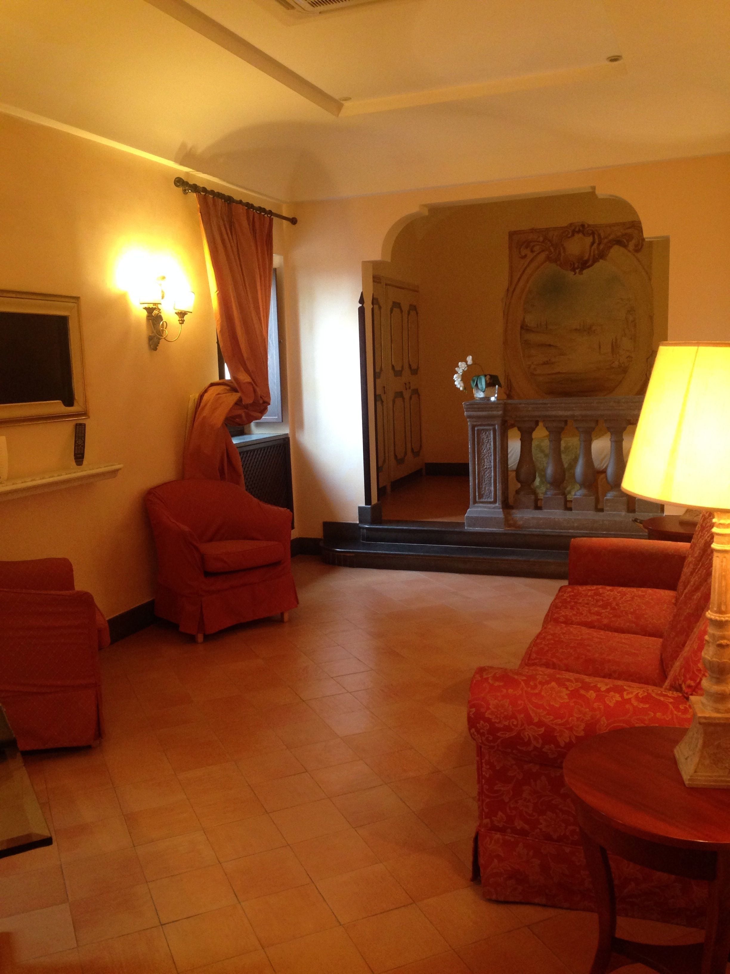 Un salon avec un canapé rouge, une petite table, un téléviseur et une cheminée.