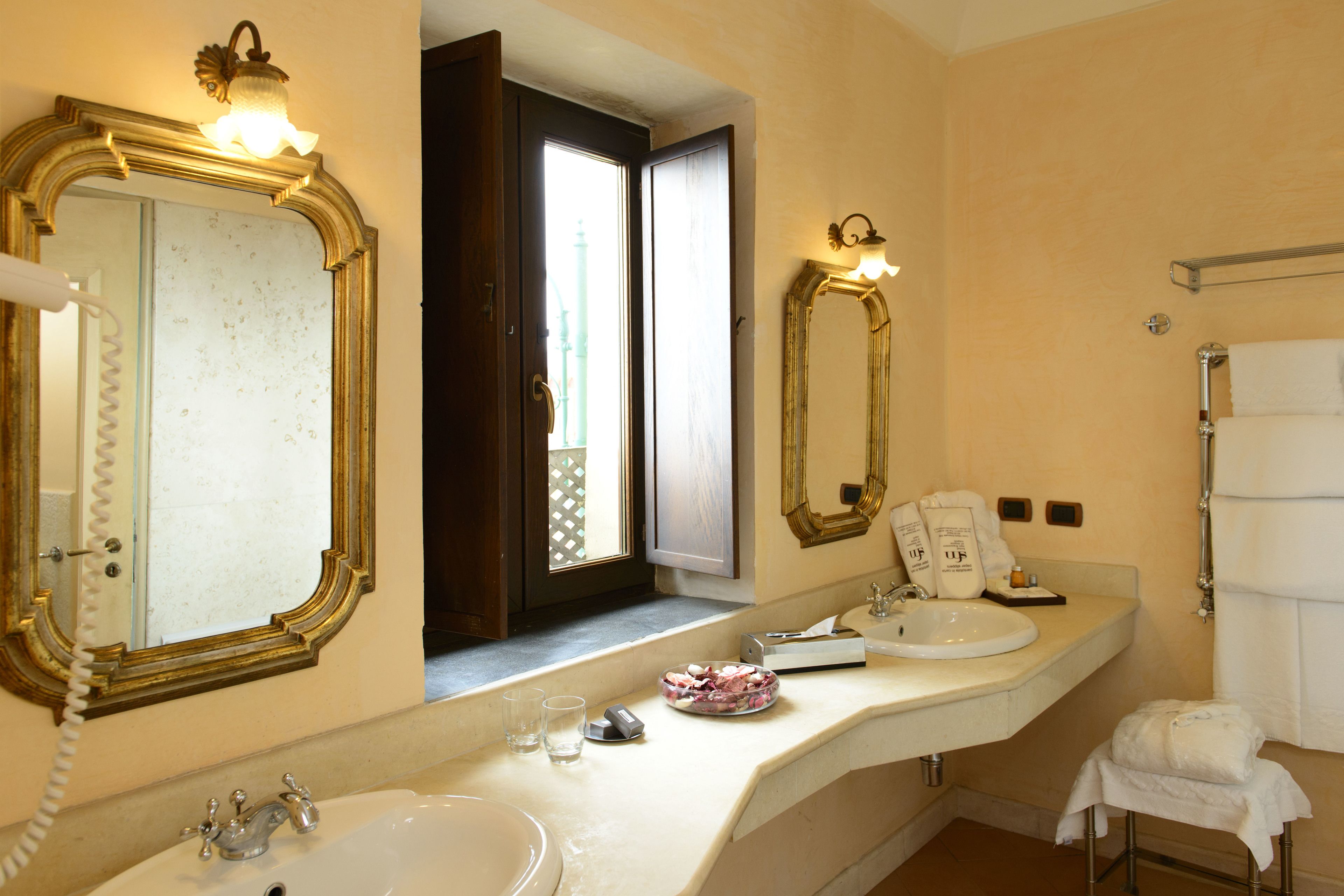 A bathroom with two sinks, a mirror, a towel rack, and a window with a view.