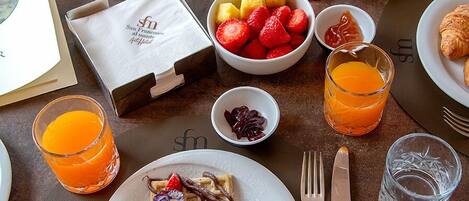 A breakfast table with plates of food, a coffee cup, and a fruit bowl.