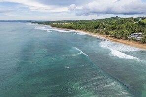 An aerial view of a coastal area with a beach, ocean, and buildings.