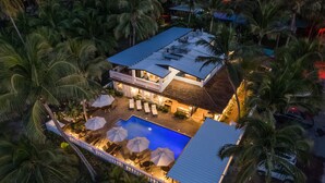 A two-story building with a swimming pool, surrounded by palm trees. - Casa Isleña Inn (Rincon)