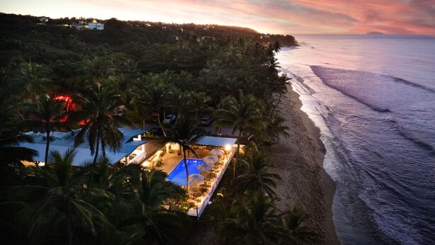 A beachfront property with a swimming pool, palm trees, and a view of the ocean. - Casa Isleña Inn (Rincon)
