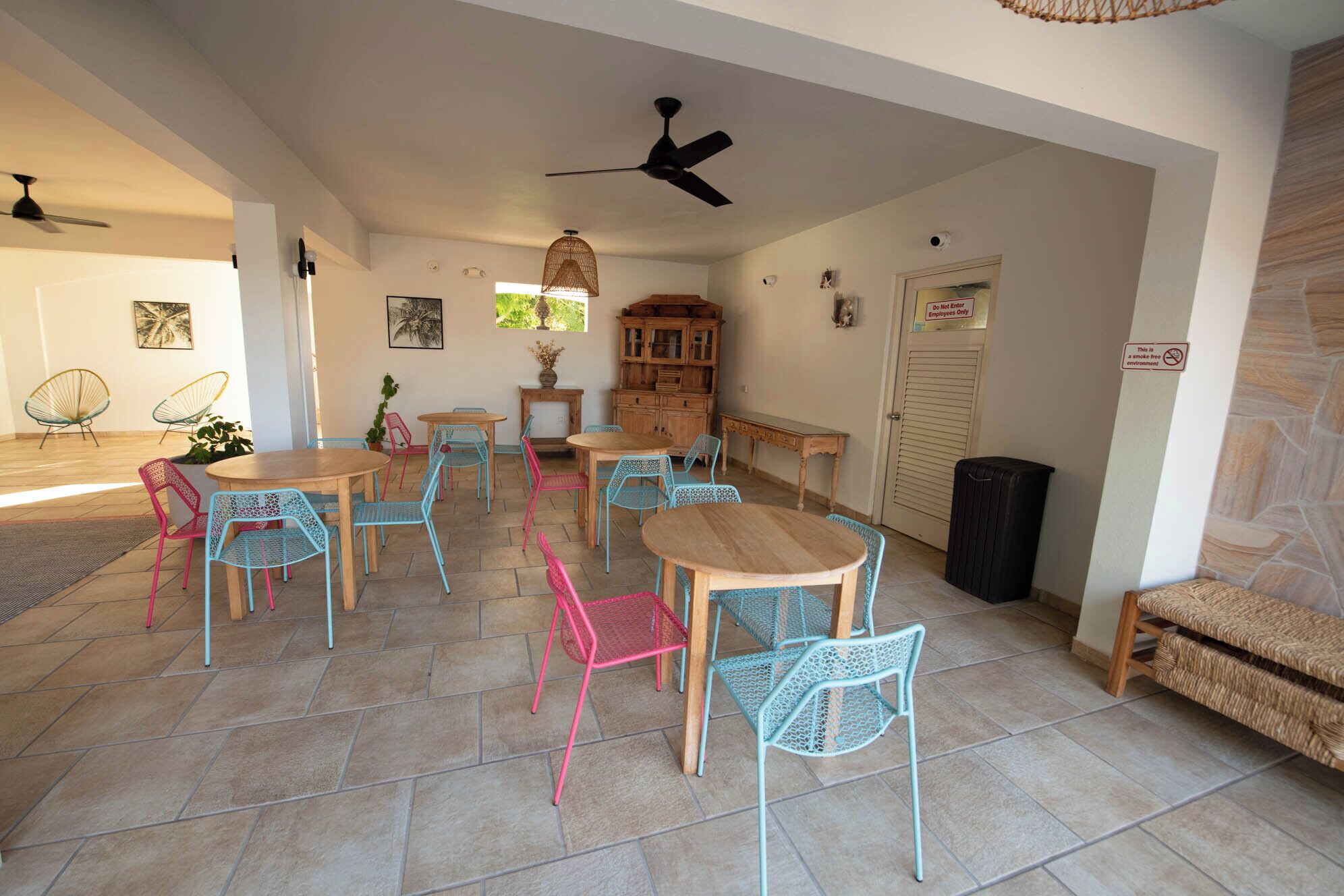 A dining area with multiple tables and chairs, a ceiling fan, and a cabinet.