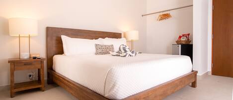 A neatly made bed with a wooden headboard, two bedside tables with lamps, and a wall-mounted towel rack.