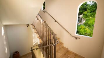 A staircase with a metal railing, a window with a view of greenery, and a tiled floor.
