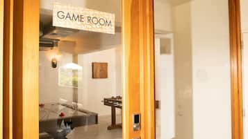 Eine holzrahmenverkleidete Tür mit einem Schild, auf dem "GAME ROOM" steht, und ein sichtbarer Innenraum mit einem Tischfußballspiel.