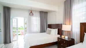 A hotel room with a large bed, a bedside table with a lamp, and a view of the outdoors through a sliding door.