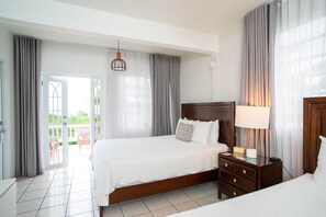 A hotel room with a large bed, a bedside table with a lamp, and a view of the outdoors through a sliding door.
