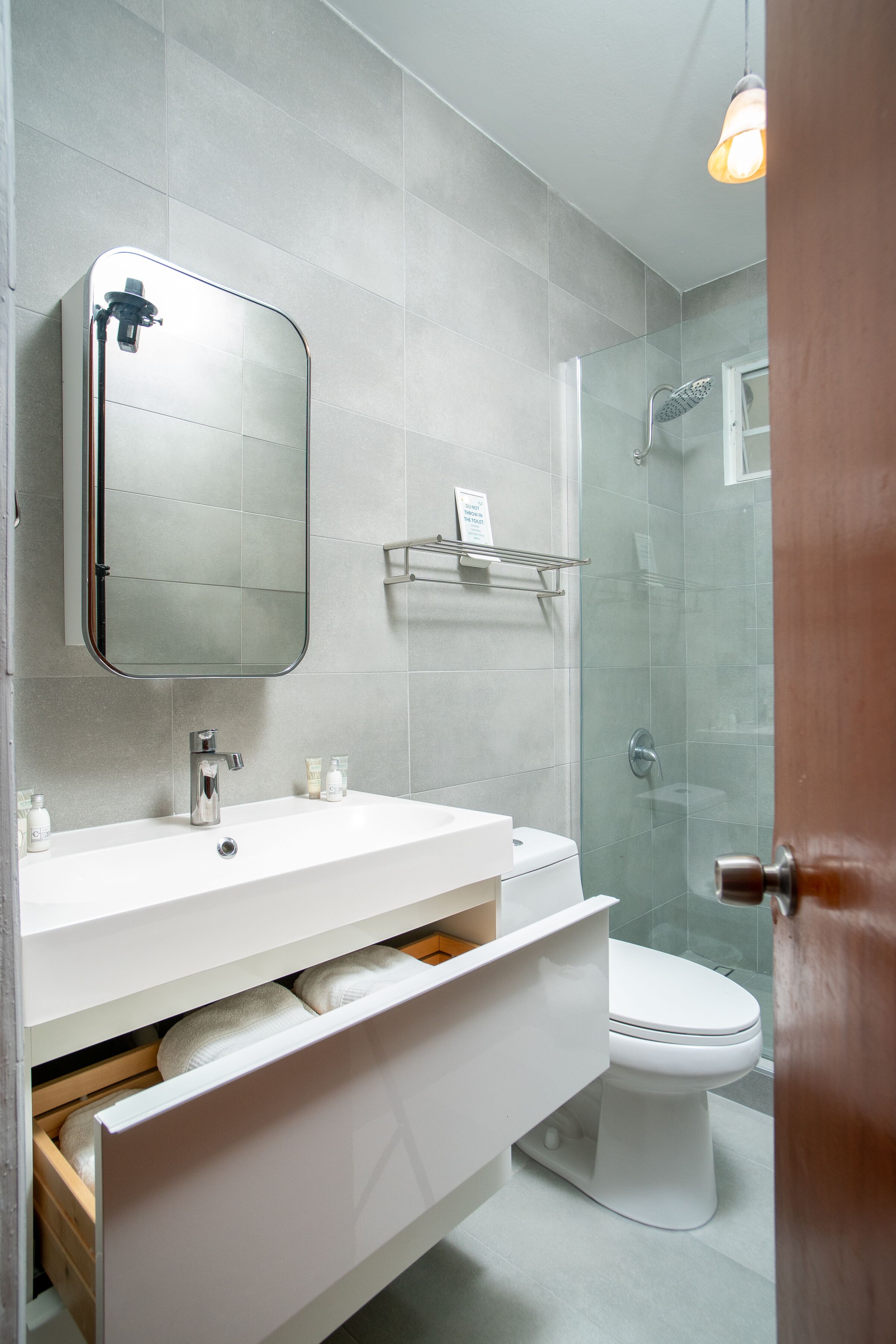 A modern bathroom with a white sink, mirror, and toilet.