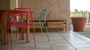 A seating area with two chairs and a bench, a potted plant, and a stone wall in the background.