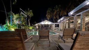 A poolside area with wooden lounge chairs and a stone building in the background.