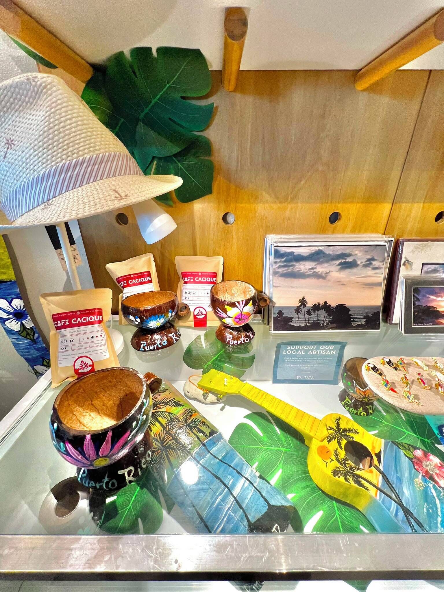 A display of coffee products, including bags and cups, with a tropical theme and a sign promoting local artisans.