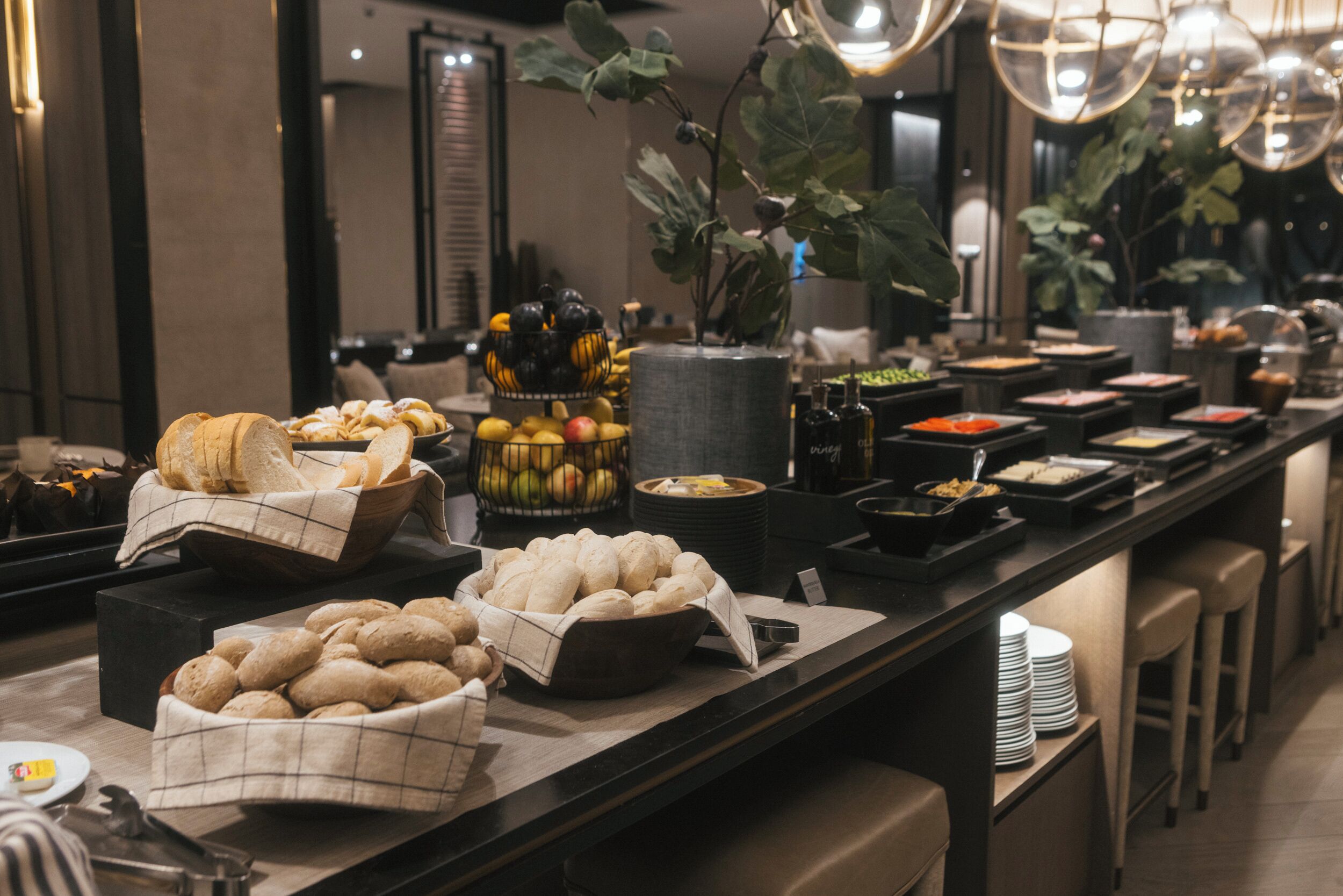 A buffet setup with various food items and a potted plant.