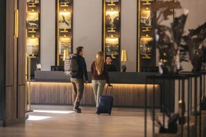 A reception area with a wooden reception desk, a large mirror, and framed artwork on the wall.