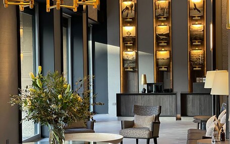 A modern lobby with a reception desk, seating area, and decorative wall panels.