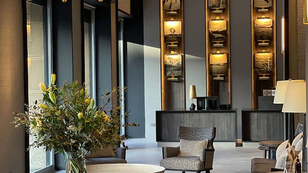 Un vestíbulo moderno con mostrador de recepción, zona de estar y paneles decorativos en la pared.
