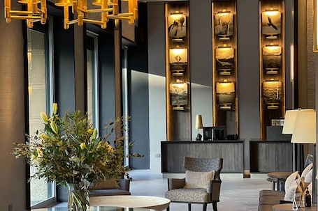 A modern lobby with a reception desk, seating area, and decorative wall panels.