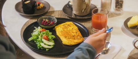 Una mesa de comedor con un plato de comida, una taza y condimentos.