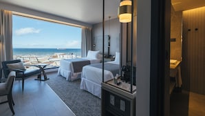 Una habitación de hotel con un ventanal grande, dos camas, un escritorio y una silla.