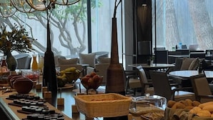 Montaje de bufé con diversos alimentos y un interior moderno con lámparas esféricas colgantes.